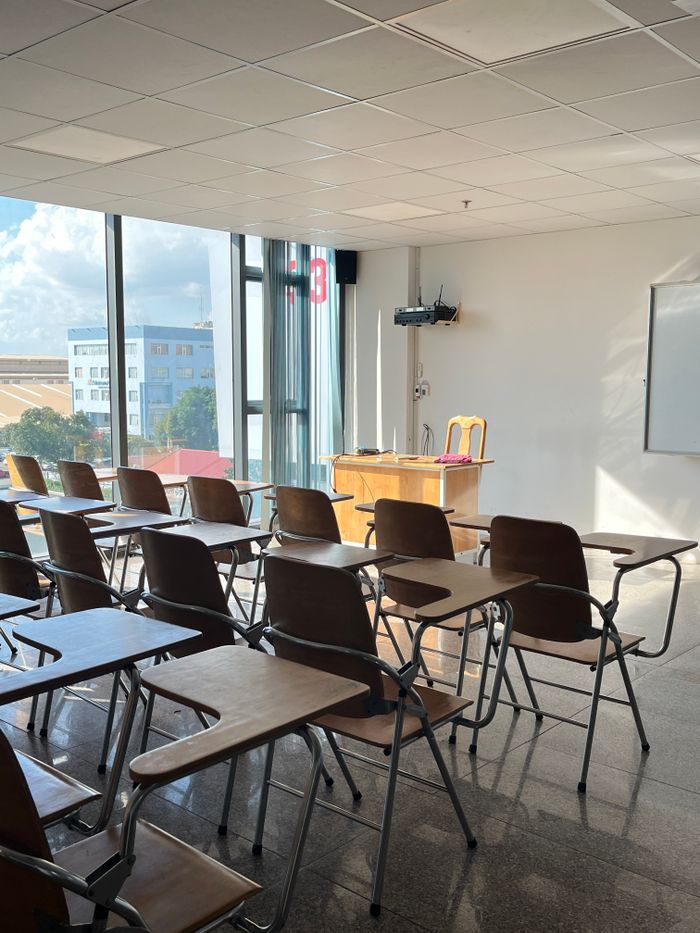 services-02 Bright, sunlit classroom with wooden desks and large windows offering a city view.