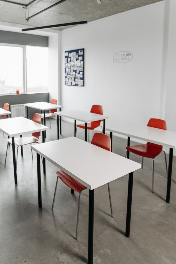 services-02 Contemporary classroom interior with red chairs and white desks arranged in rows.