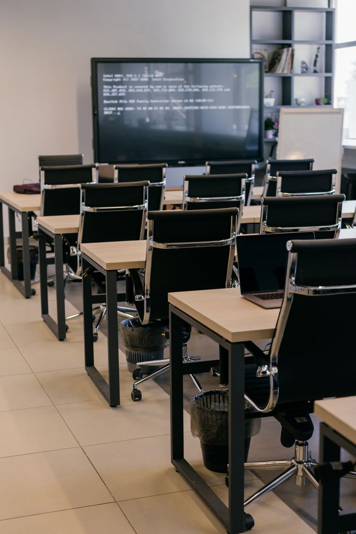 about-01 Contemporary office space with sleek black leather chairs and a large screen for presentations.